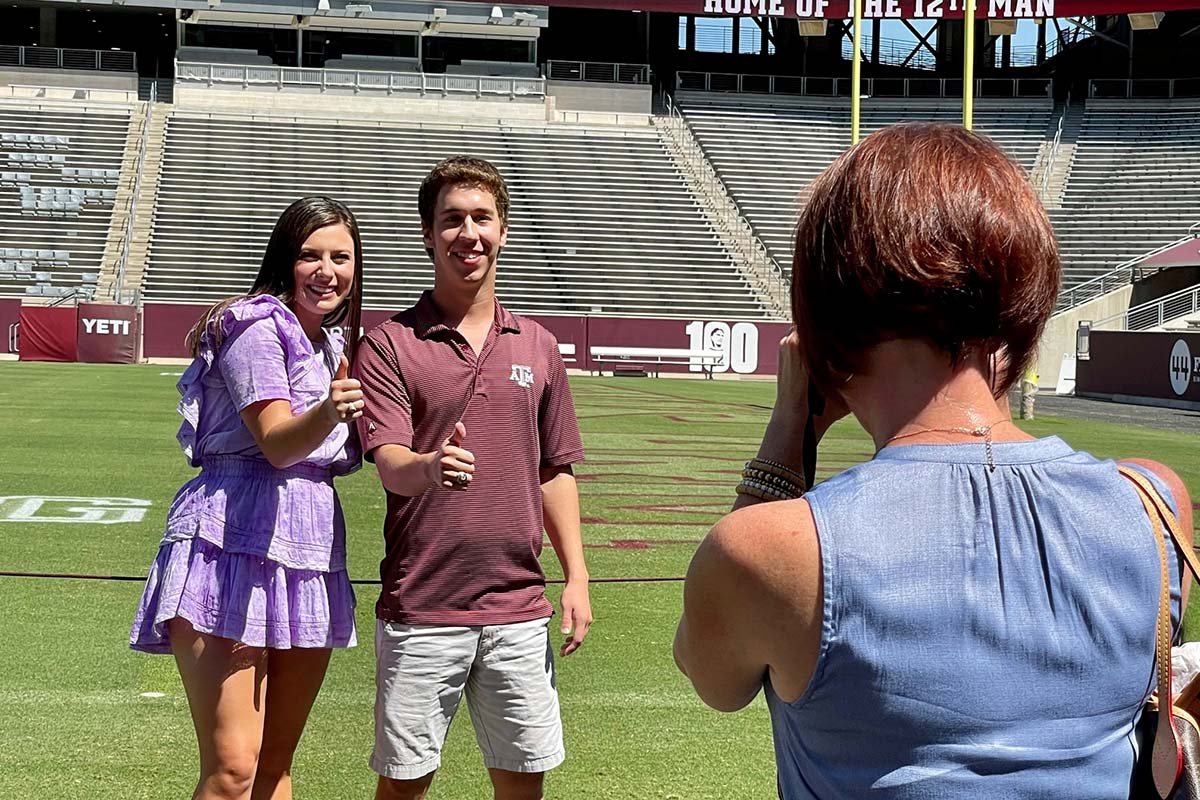 Two people posing on field with thumbs up