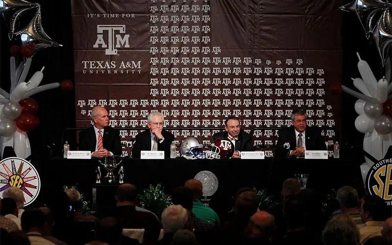Men in suits at podiums with crowd in foreground