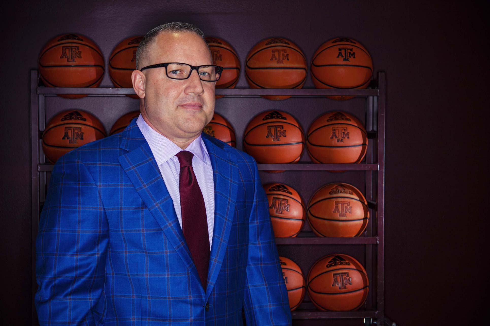 Buzz Williams standing in front of a rack of basketballs