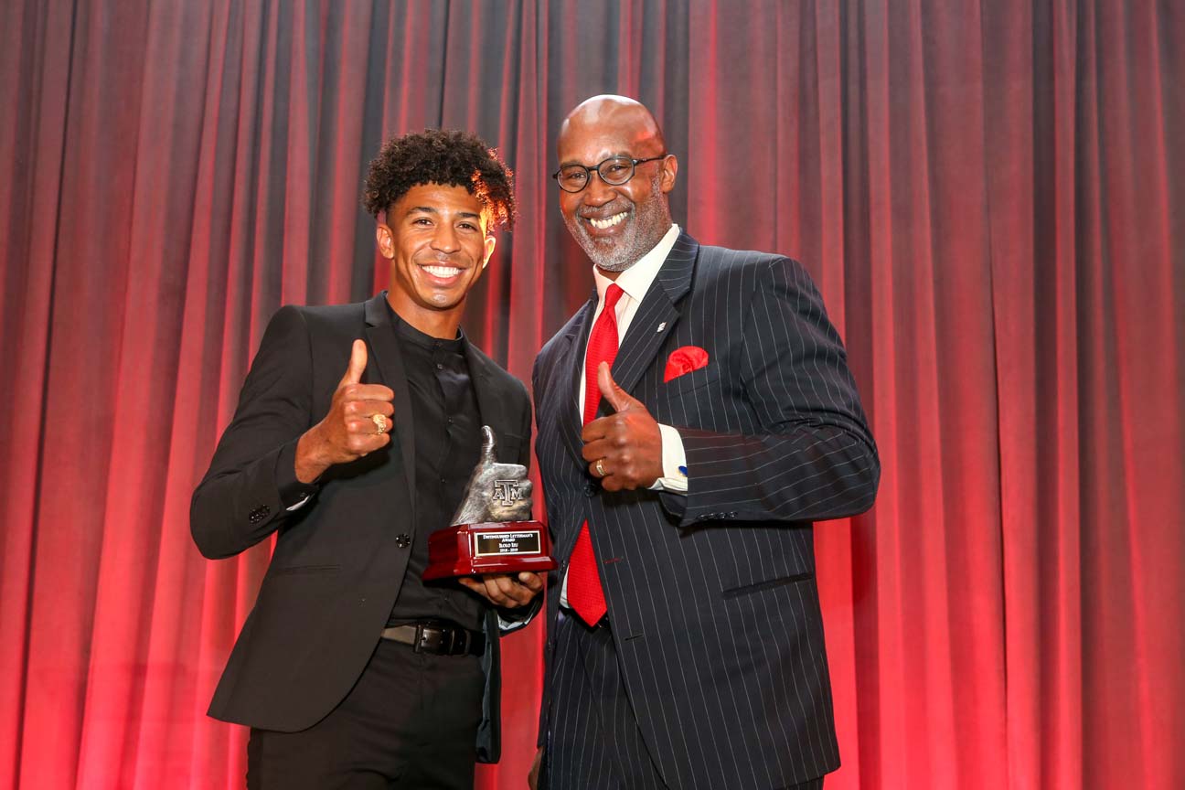 A student-athlete and another gentlemen posing with an award