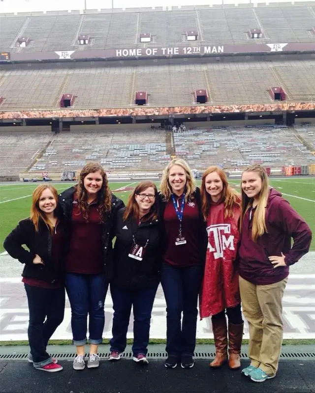 A group of girls posing together on the side of the field